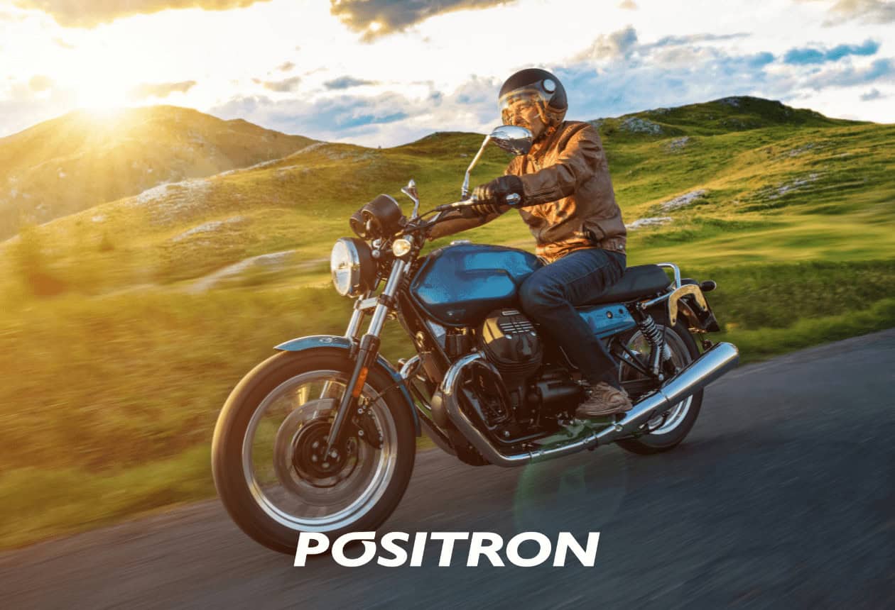 homem de capacete pilotando moto, com montanhas ao fundo